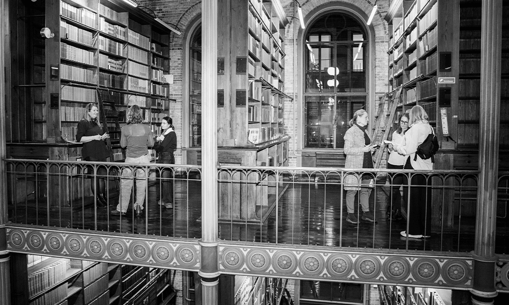 Mennesker står i hver sin bås af bøger på gammelt bibliotek